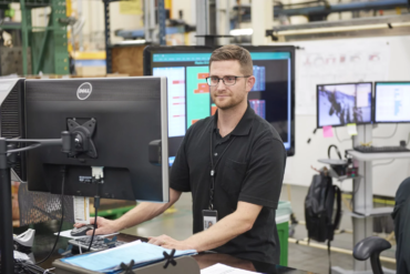 Man Standing By Desktop Computer - CBM CONNECT